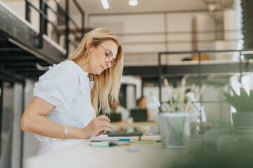 A persistent businesswoman browsing data, working alone in an office. They analyze market research, optimize strategies, and aim for profitability.