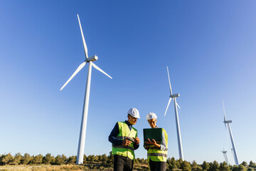 Engineers using laptop while working in wind energy field.
