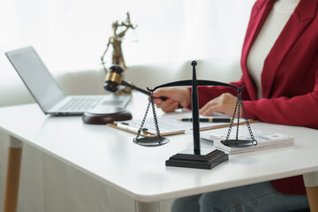Attorney's office. Goddess of justice with scales and lawyer working on laptop Law, advice and justice concept Lawyer reads contract Young female lawyer or lawyer working in the office
