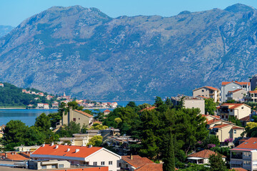 Naklejka na ściany i meble view of the old town of Kotor in Montenegro and the coast of the Bay of Kotor, the sea and medieval European architecture, city streets, red tiled roofs, the concept of traveling across the Balkans