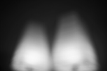 An abstract illusion of a lamp shining in the darkness in grayscale.