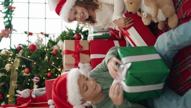 Adorable boy and girl celebrating christmas unpacking gift at home