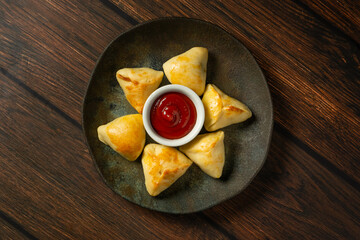 esfiha roasted or baked party snack known as 'salgadinho de festa' on a dark plate