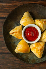 esfiha roasted or baked party snack known as 'salgadinho de festa' on a dark plate