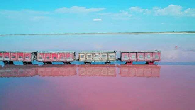 Aerial of an old train standing on the railway in salt lake Bursol. Salt mining at pink lake in Altai region of Russia