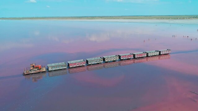 Aerial panorama of an old train standing on the railway in salt lake Bursol. Salt mining at pink lake in Altai region of Russia