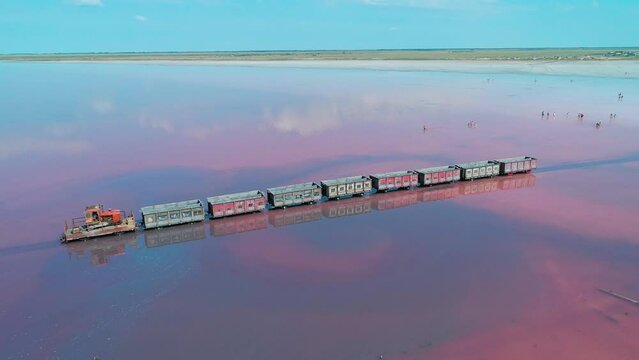 Aerial panorama of an old train standing on the railway in salt lake Bursol. Salt mining at pink lake in Altai region of Russia