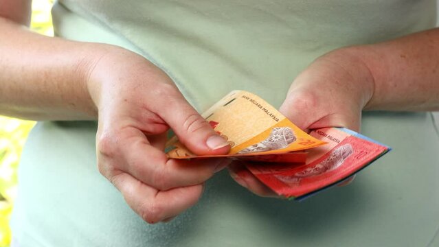 Malaysia money, Woman counting ringgit in hand, Banknotes of smaller denominations, 20, 10, 5, and 1, financial budget concept