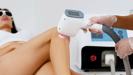 Flash of diode laser hair removal, cosmetologist removes hair on beautiful female legs, hair...