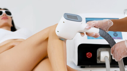 Flash of diode laser hair removal, cosmetologist removes hair on beautiful female legs, hair removal for smooth skin, laser procedure in a beauty studio or clinic, body care hair removal.