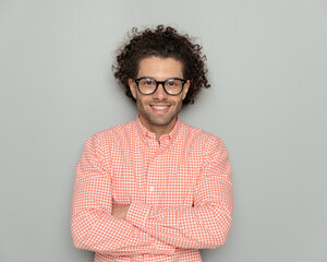 portrait of smart casual man with curly hair and glasses crossing arms