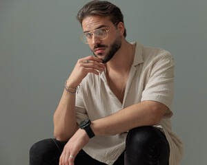 cool bearded guy with glasses holding elbows on knees