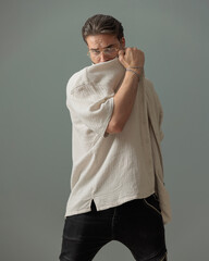 cool young man with glasses covering face with shirt and posing