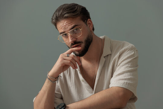seductive young man with glasses touching lips and looking forward