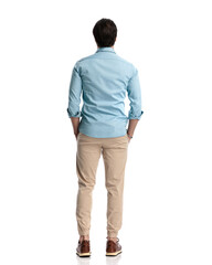 rear view of casual man in denim shirt with chino pants holding hands in pockets