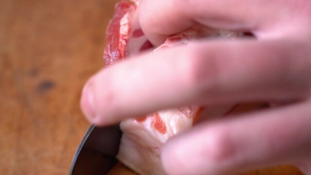 Slicing of salted pork fatback on cutting board, close-up. Ukrainian traditional food - salo	
