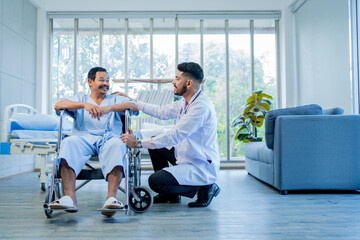 male doctor supports patient female sitting on wheelchair. Attractive male specialist medical doctor doing physical therapy procedure for mature female for health care in hospital ward.