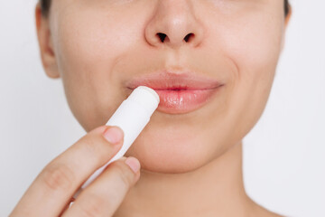 Cropped shot of a young caucasian attractive woman applying a hygienic lipstick on her lips on a...
