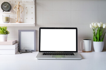 Fototapeta premium Front view laptop, coffee, notebook and houseplant on white table. Blank screen for your advertise text.
