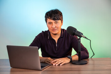 Portrait of asian man recording a video blog in a studio with microphone