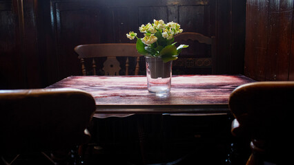 Flowers in the middle of a wooden tables surrounded by chairs