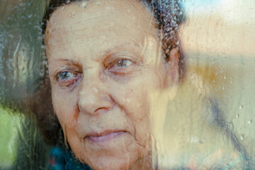 Elderly woman sadly looking out the window