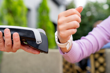 Woman paying contactless with smartwatch in restaurant