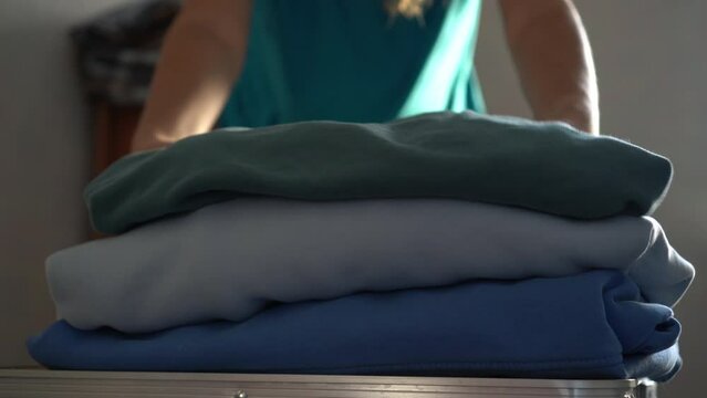 Woman donates her warm clothes. Sale of used clothes. Donation. Woman folds clothes, close up. Moving to a new house, putting things in boxes. Home routines, clothing storage, stack clothing