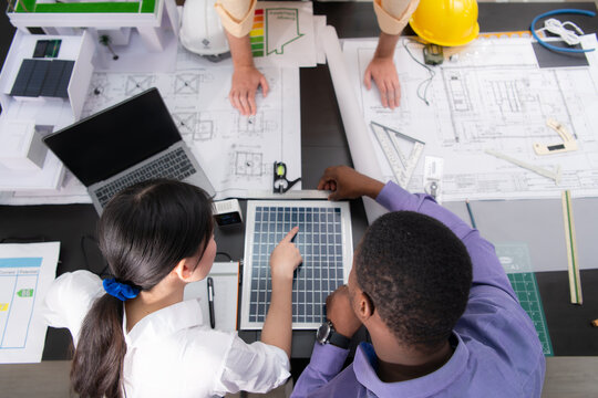 A multi-national team of architects and designers is meeting to brainstorm designs for solar cell panels for office and residential buildings - Powered by Adobe