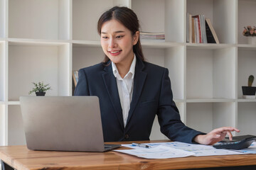 businesswoman using calculator for do math finance on wooden desk in office and business working background, tax, accounting, statistics and analytic research concept