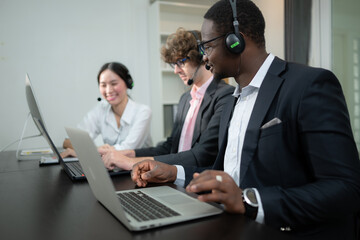 Group of business people wearing headset working actively in office. Call center, telemarketing, customer support agent provide service on telephone video conference call.