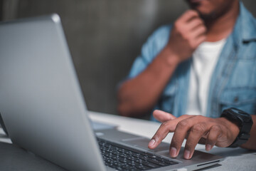 A business man is checking daily online stock market prices through a laptop at home with graphs...