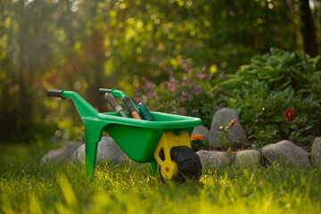 A baby cart is standing by a flower bed. Helping parents in the garden. Landscape design with your own hands.