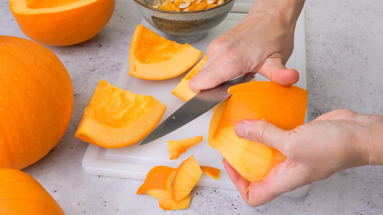 Woman hands peeling fresh raw orange pumpkin, close up