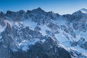 The Caucasus Mountains in Georgia are a stunning sight, especially when covered in snow against a clear blue sky. The contrast between the white snow and the deep blue sky is breathtaking.