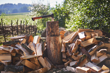 Pile of chopped birch and pine fire wood around the chopping block with modern style heavy axe....