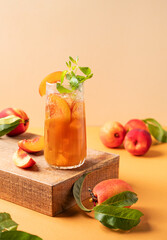 Refreshing peach ice and mint tea. Homemade cold summer drink on an orange background with fresh fruits.