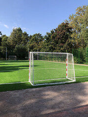 Fototapeta premium empty school football field, gates in the foreground, green lawn, landscape