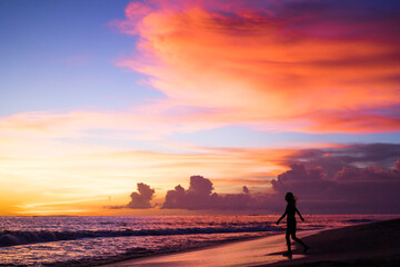 people on the beach at sunset. the girl is jumping against the backdrop of the setting sun.