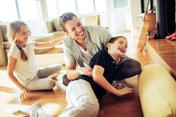 Fototapeta premium Young Caucasian father playing with his children in the living room at home