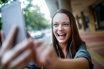 Young Caucasian woman having a video call on her smartphone while commuting in the city
