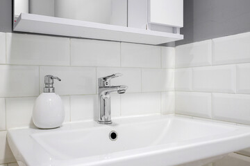 Chrome faucet with white ceramic sink in the bathroom