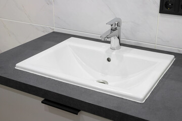 Chrome faucet with white ceramic sink in the bathroom