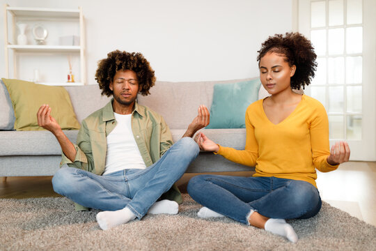 Black Couple Meditating With Eyes Closed Practicing Yoga At Home