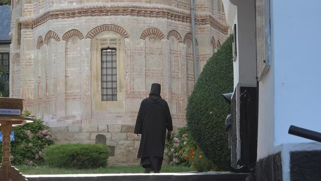 Rear view of black dressed nun walking to the monastery yard