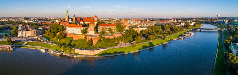 Krakow, Poland. Wide aerial panorama of old town at sunset with Royal Wawel castle and cathedral. Vistula river banks, tourist boats, harbors, parks, promenades. boulevards  and walking people