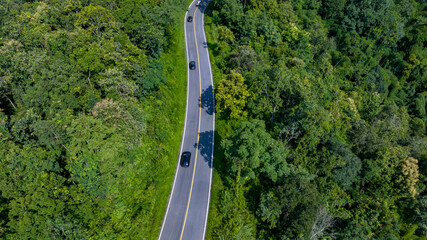 Aerial top view road in forest with car motion blur. Winding road through the forest. Car drive on the road between green forest. Ecosystem ecology healthy environment road trip.