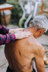 An adult woman, a professional doctor, makes a relaxing massage to a sick old elderly gray-haired retired man with scoliosis on his back. Photography, lifestyle.