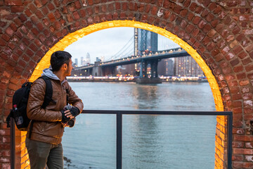 Man standing near brick arch and looking at the Manhattan bridge