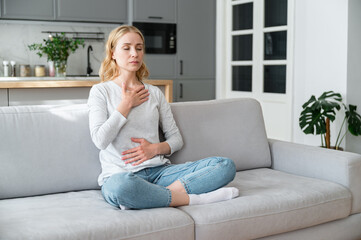 Mindful woman breathing deeply and managing stress at home - obrazy, fototapety, plakaty